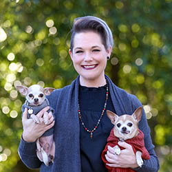 Dr. Rebecca Rader holding two small chihuahuas wearing sweaters