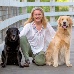 Dr. Sarah Thompson with her Black Labrador and Golden Retriever sitting on a bridge